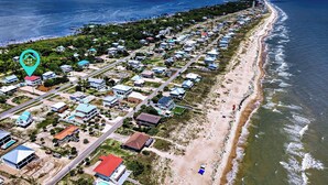 Vista aérea de una zona residencial costera con casas, una playa y un muelle.