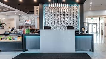 A modern reception area with a central desk, a patterned wall, and a chandelier.