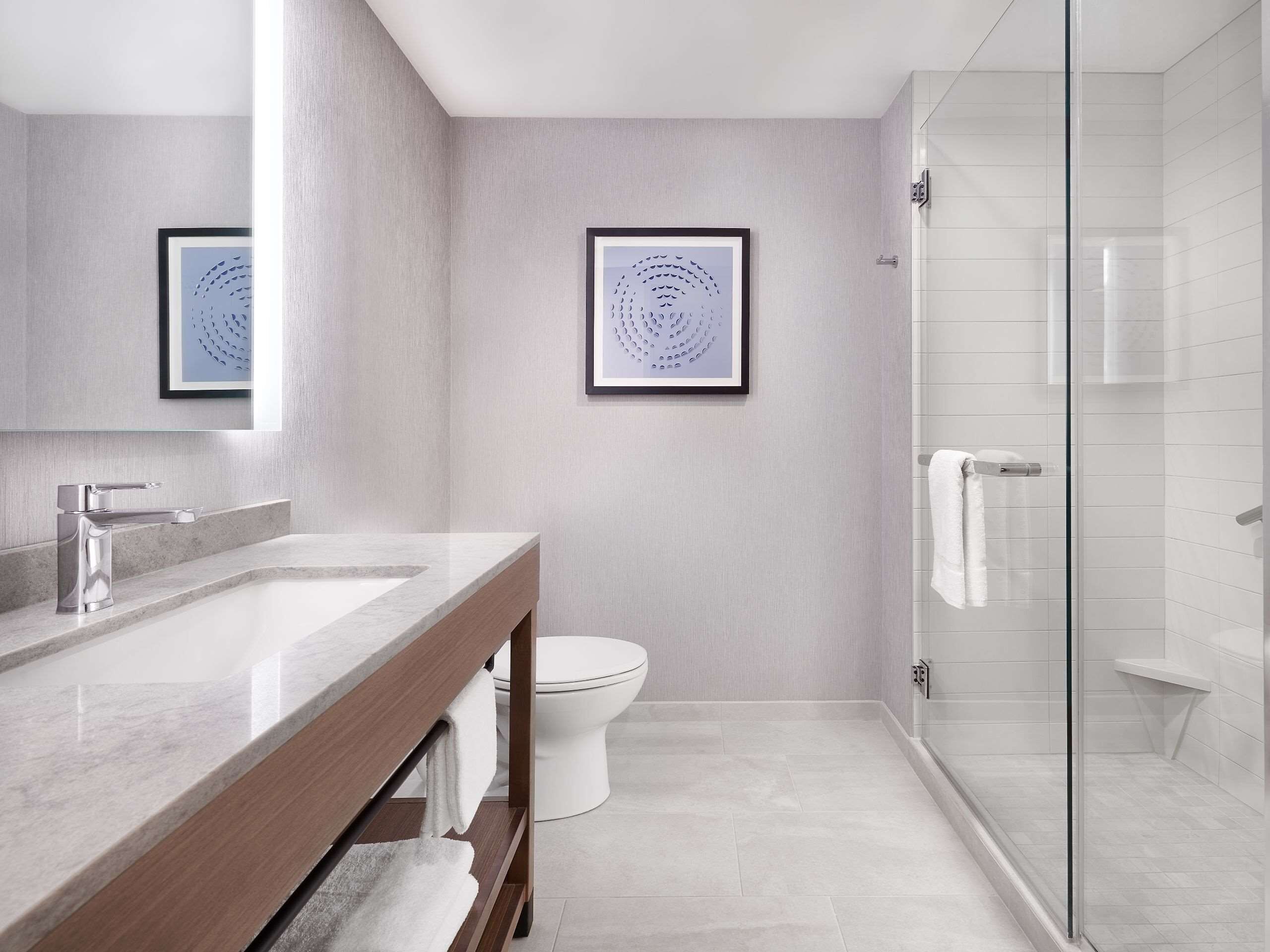 Un baño moderno con lavamanos de mármol, inodoro y cabina de ducha de vidrio.