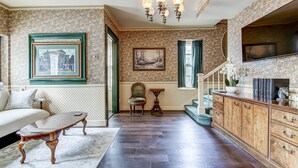 A spacious living room with a large sofa, a wooden coffee table, a chandelier, and a staircase leading to an upper level. - Spacious Carriage House | Private Entrance | Historic & Stylish (Springfield)