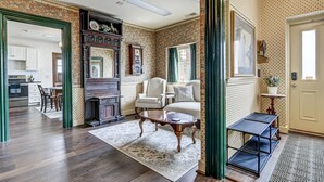A spacious living room with a fireplace, a dining area, and a kitchen in the background. - Spacious Carriage House | Private Entrance | Historic & Stylish (Springfield)