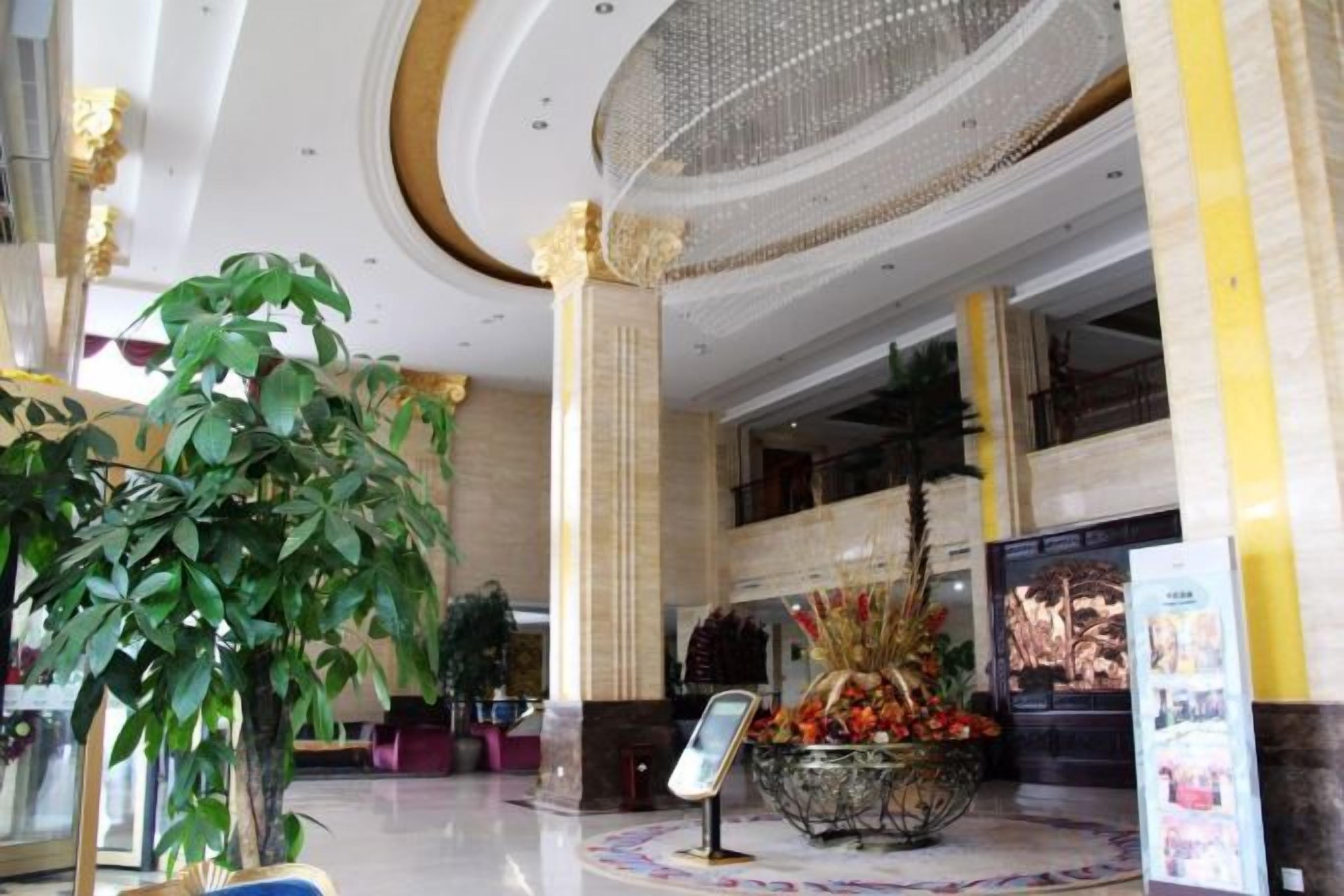 A lobby with a reception desk, a large decorative plant, and a chandelier.