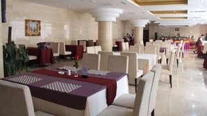A spacious hotel dining area with multiple tables and chairs, a clean and modern interior, and a large pillar in the center. - Anhua Hotel (Wei County)
