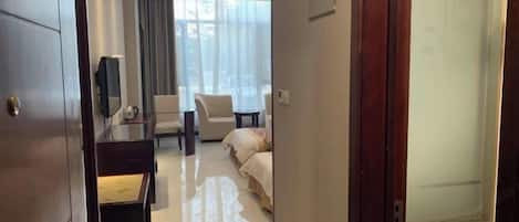 A hotel room with a bed, a desk, a chair, and a TV.
