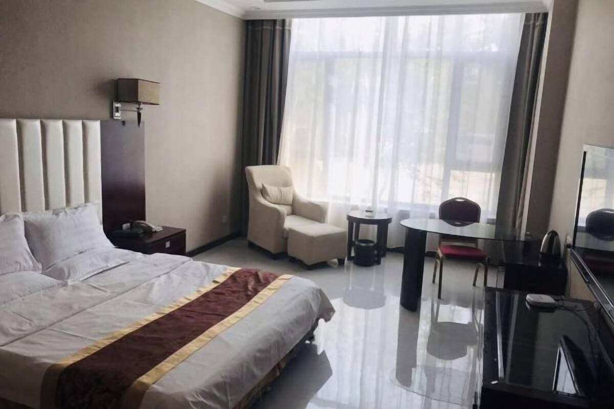 A hotel room with a large bed, a chair, a small table, and a TV.