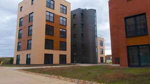 Een modern meerlaags gebouw met een combinatie van baksteen en beige gevels, met balkons en grote ramen.