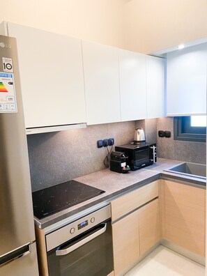 A modern kitchen with white cabinets, a stainless steel refrigerator, a built-in oven, a microwave, and a sink. - Luxury Suite in Halkidiki Greece (Flogita)