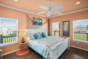 A bedroom with a bed, a ceiling fan, a window with blinds, and a painting on the wall.