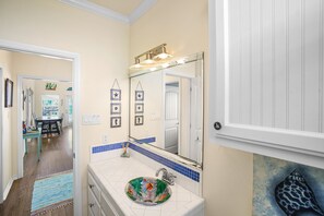 Bathroom features a large mirror above a sink with a decorative glass bowl, blue and white tiles, and a framed picture on the wall.