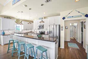 A modern kitchen with white cabinetry, stainless steel appliances, and a central island with bar stools.