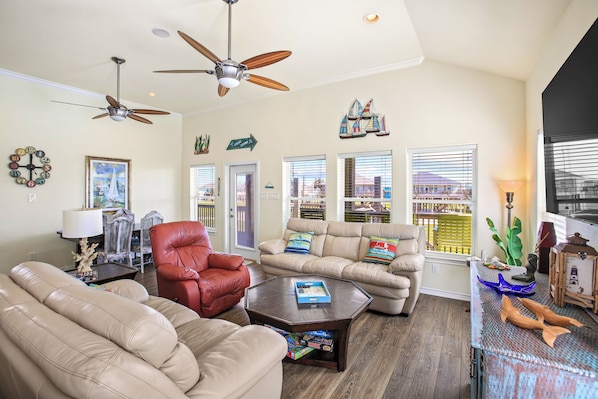 A living room with a sofa, armchair, coffee table, and ceiling fans.