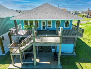 A two-story house with a deck, a covered porch, and a small outdoor kitchen area.