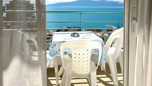 A balcony with a table and chairs, overlooking a body of water and mountains. - ERAL Apart-Hotel (Sarandë)