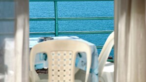 A view from a window with a chair, a railing, and a mountain range in the distance. - ERAL Apart-Hotel (Sarandë)