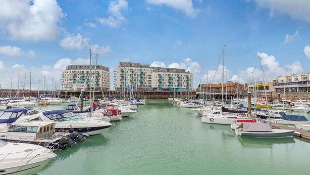 A marina with numerous boats docked, surrounded by multi-story buildings with balconies. - On the Water 2 -waterside Studio With Terrace Overlooking the Harbour (Brighton)