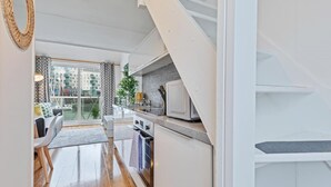 A modern kitchen with a microwave, a dining area with a table and chairs, and a view of a cityscape through large windows. - On the Water 2 -waterside Studio With Terrace Overlooking the Harbour (Brighton)