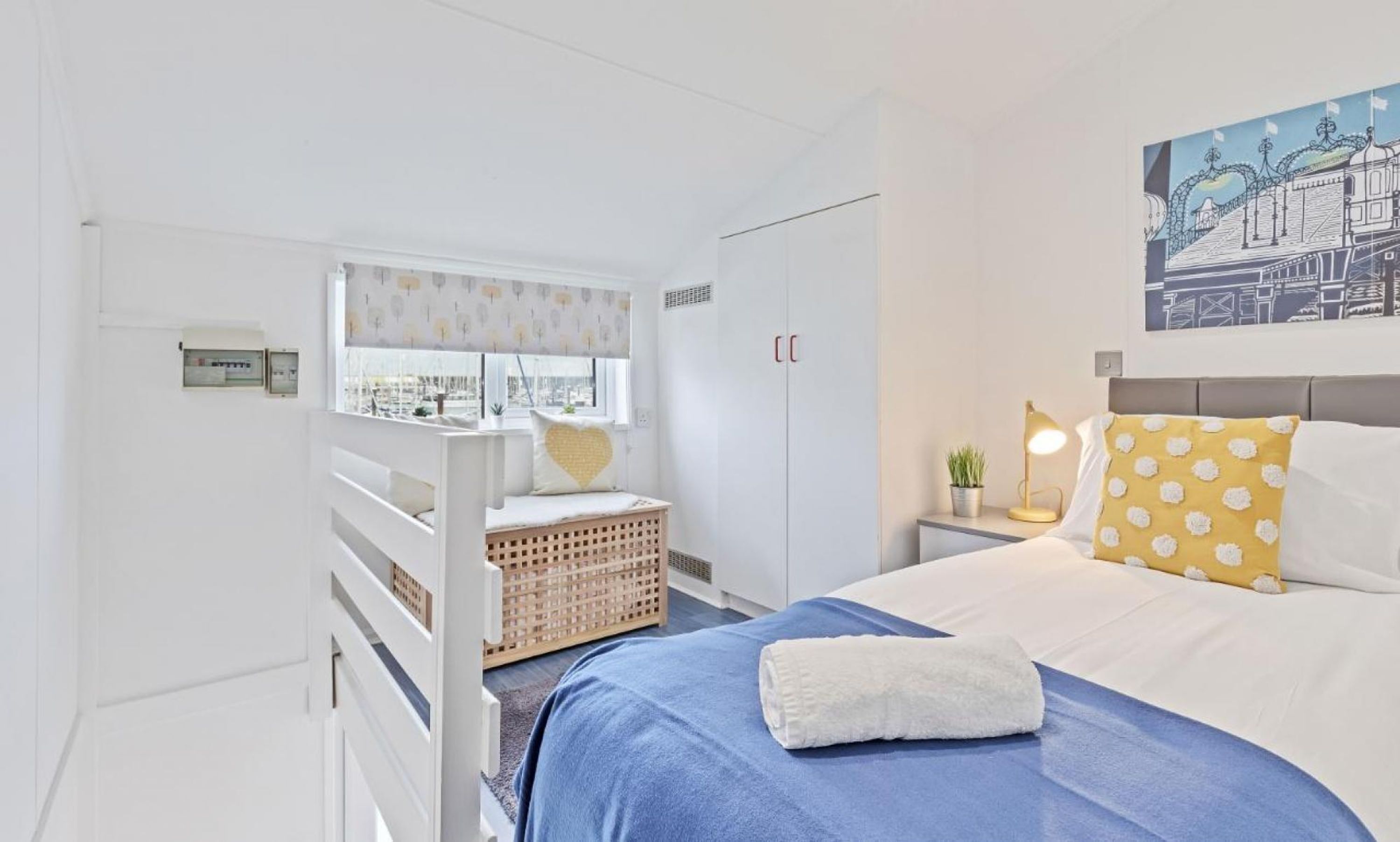 A bedroom with a bed, a nightstand, a window, a wardrobe, and a wall-mounted painting.