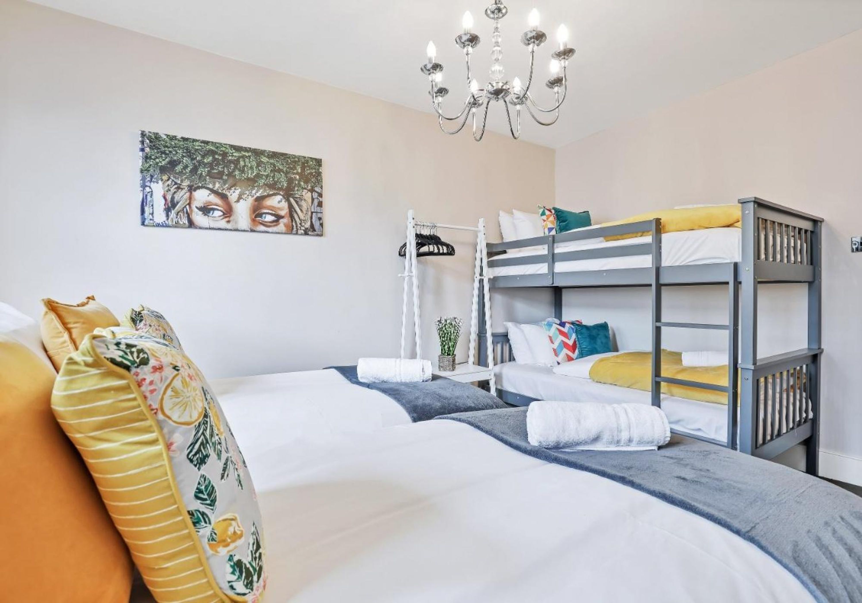 A bedroom with bunk beds, a chandelier, a painting, and a potted plant.