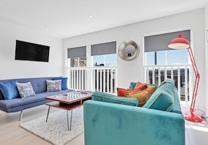 Un salon moderne avec un canapé, des fauteuils, une table basse et un lampadaire rouge.