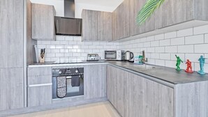 Una cocina moderna con armarios grises, horno empotrado, microondas y tostadora.