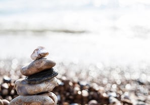 A stack of smooth stones on a pebbly beach with a blurred water background. - Right On Bright On Apartment 1E - City Centre Luxury Apartments (Brighton)