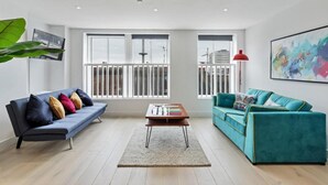 A modern living room with a blue sofa, teal sofa, and a coffee table. - Right On Bright On Apartment 1E - City Centre Luxury Apartments (Brighton)