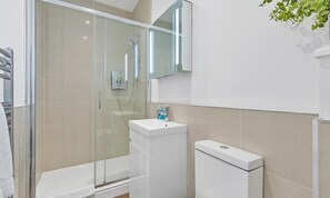 A modern bathroom with a glass-enclosed shower, a white sink, and a toilet.