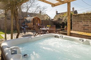 A hot tub with a wooden pergola overhead, surrounded by outdoor furniture and a brick wall. - LUXURY: JACUZZI, SAUNA, FIREPLACE, DOGS WELCOME (Stoke Ash)