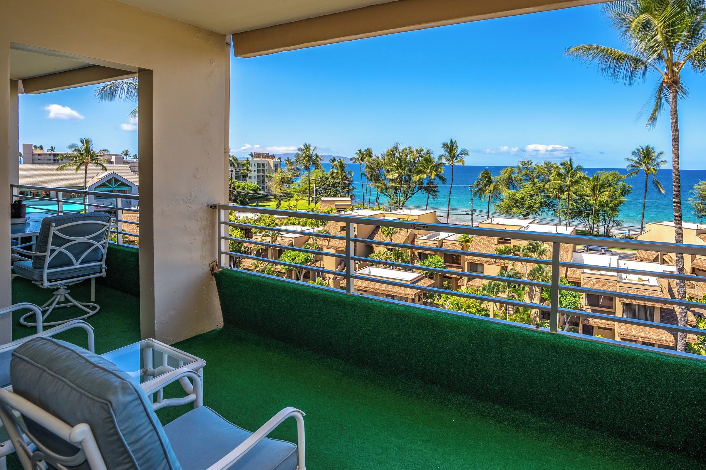 Un balcón con vista a la playa, palmeras y edificios de hotel.