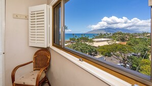 A balcony with a view of a coastal landscape, including a mountain and a beach.