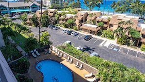 A resort with a swimming pool, lounge chairs, and a view of the ocean.