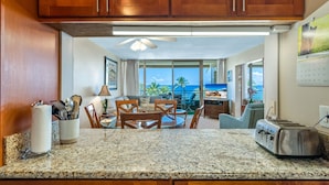 A kitchen with granite countertops, wooden cabinets, and a view of the ocean.