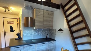 Una cocina compacta con una mesa de madera, armarios empotrados y una campana extractora de acero inoxidable.