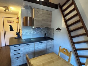 Una cucina compatta con un tavolo di legno, mobili a incasso e una cappa aspirante in acciaio inossidabile.