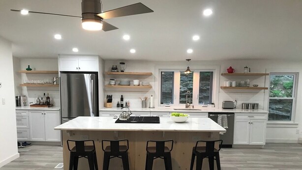 Una cocina moderna con una isla central, taburetes de bar y un refrigerador.
