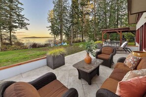 An outdoor patio with wicker furniture, a stone table, and a barbecue area.