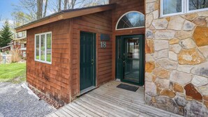 Une cabane en bois avec une façade en pierre, une porte verte et une plaque portant le numéro 18.