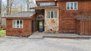 Une maison à deux étages avec une façade en pierre, une porte verte et un petit porche.