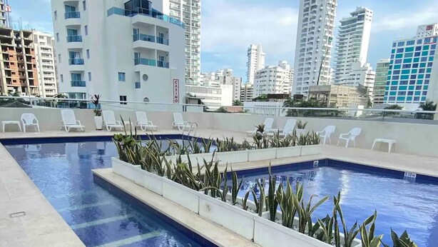 Une piscine sur le toit, agrémentée de chaises longues et de plantes en pot.