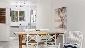 A modern kitchen with white cabinets, a wooden dining table, and white chairs.