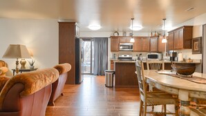 A kitchen with wooden cabinets, a microwave, a stove, and a dining area with a table and chairs.