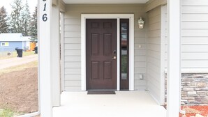 A house with a brown front door, a number '316' on the wall, and a small porch area with a light fixture.