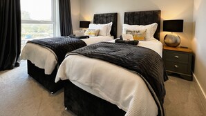 Habitación doble con dos camas, una mesita de noche con lámpara y una ventana con cortinas.