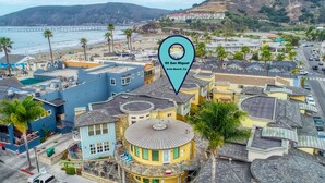 A coastal residential area with a mix of single-story and multi-story buildings, featuring a prominent blue building with a circular tower. - Sandcastle at Avila a Family Condo, Steps to Beach (Avila Beach)