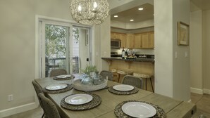 A dining area with a wooden table set for six, surrounded by wicker chairs. A decorative glass centerpiece is on the table. - Sandcastle at Avila a Family Condo, Steps to Beach (Avila Beach)