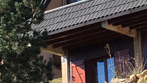 Ein Haus mit einem geneigten Dach, einem sichtbaren Dachfenster und einem Steinfundament.