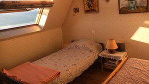 Ein kleines, gemütliches Schlafzimmer mit einem Einzelbett, einem Nachttisch, einer Lampe und einem Fenster mit Blick.