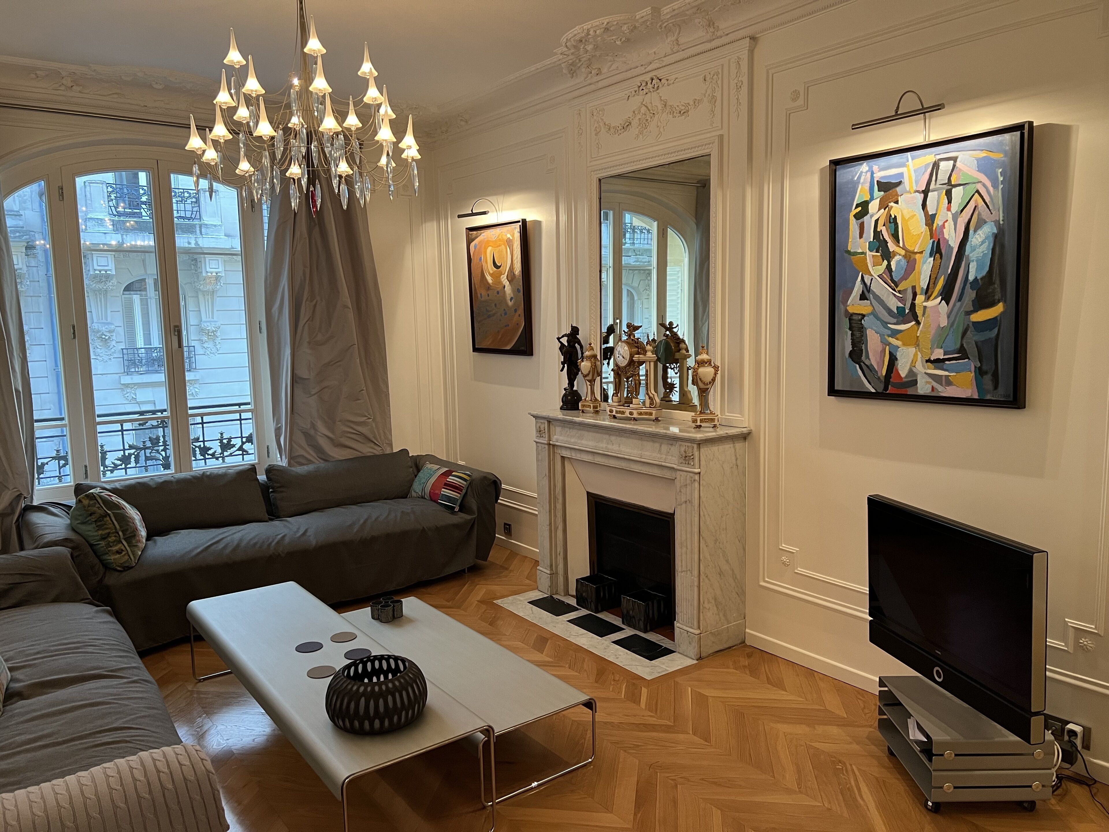 Ein Wohnzimmer mit einer Couch, einem Couchtisch, einem Kamin, einem Fernseher und Kunstwerken an den Wänden.