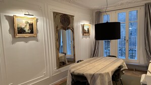 Ein Esszimmer mit Tisch für vier Personen, einem großen Spiegel und gerahmten Kunstwerken an den Wänden.
