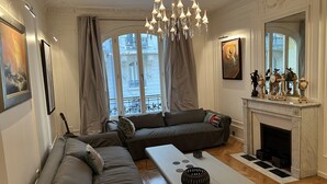 Ein Wohnzimmer mit einer Sofagarnitur, einem Couchtisch, einem Kamin und einer Kristallleuchter.